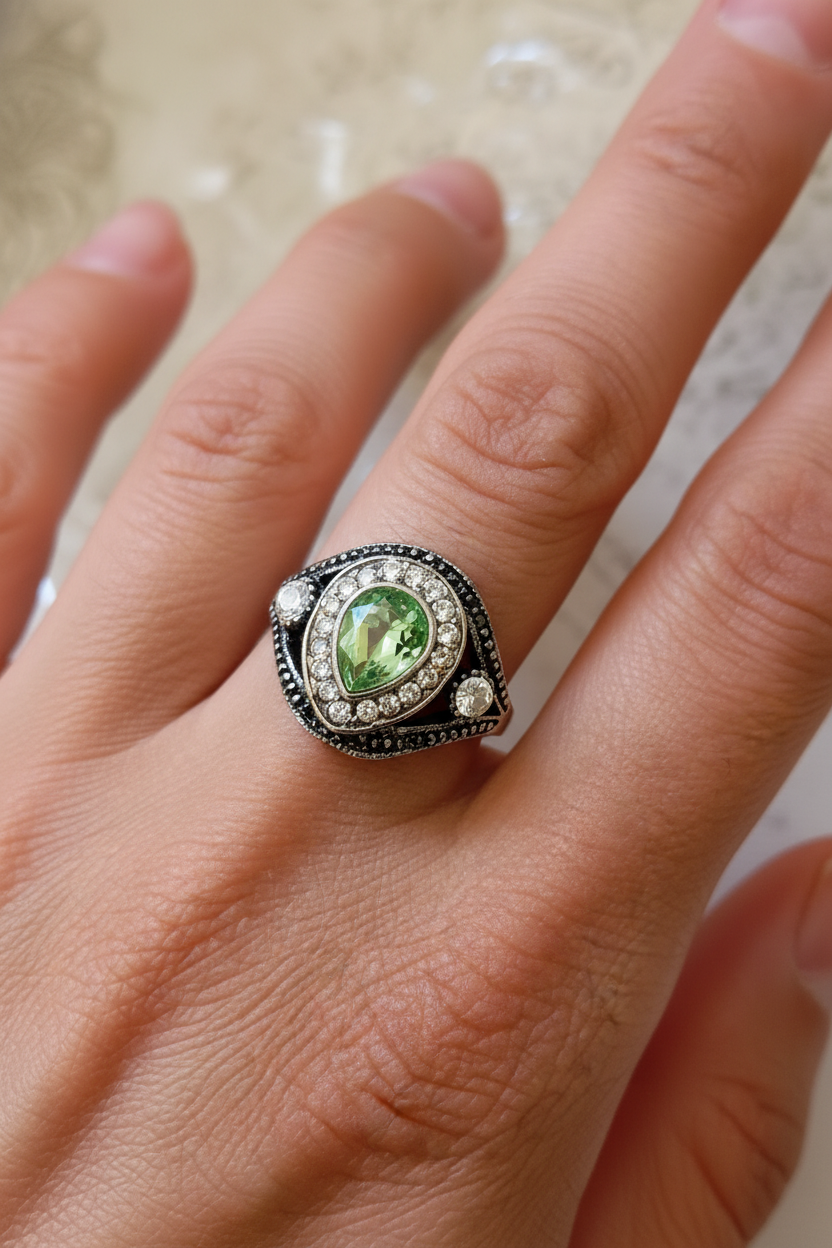 Mano de mujer con anillo de peridoto verde en gota